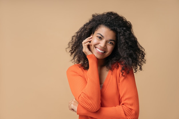 Linda mulher afro-americana sorridente com penteado encaracolado, olhando para a câmera