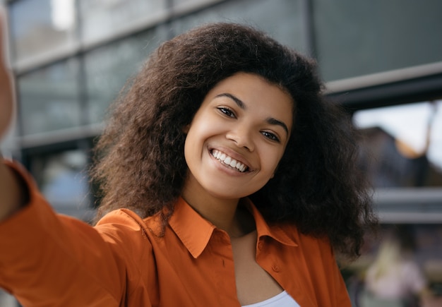 Linda mulher afro-americana tomando selfie no celular. Blogger fazendo streaming de vídeo on-line