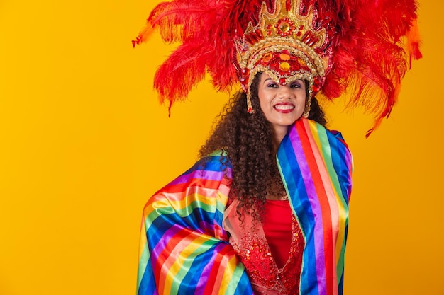 Linda mulher afro com roupa de carnaval de bandeira lgbt em fundo amarelo.