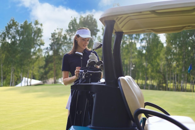 Foto linda mulher alegre de pé perto no carrinho de golfe.