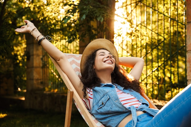 Foto linda mulher alegre e cacheada ao ar livre no parque descanse