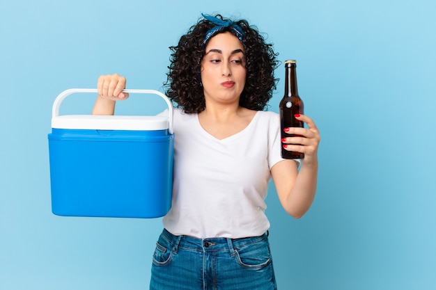 Linda mulher árabe com uma geladeira portátil e uma cerveja