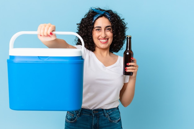 Linda mulher árabe com uma geladeira portátil e uma cerveja