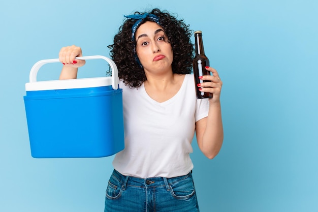 Linda mulher árabe com uma geladeira portátil e uma cerveja