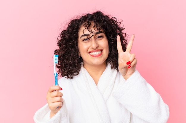 Foto linda mulher árabe usando roupão de banho e escova de dentes