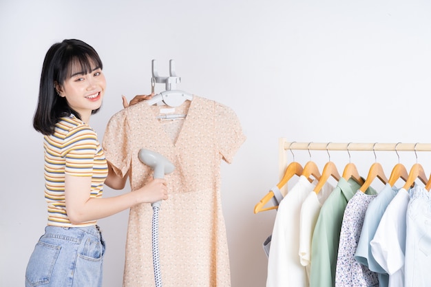 Linda mulher asiática alisando o vestido com o ferro a vapor