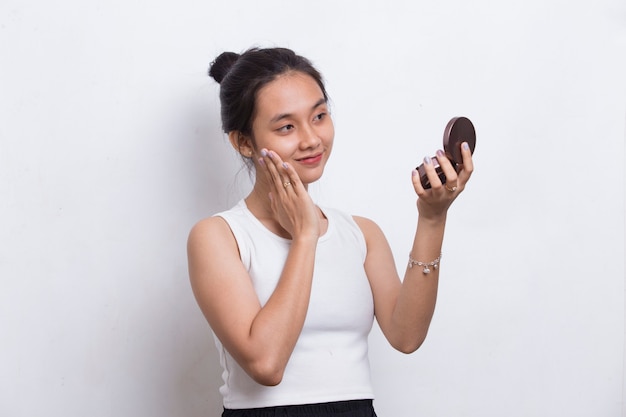 Linda mulher asiática aplicando pó na maquiagem do cosmético isolado no fundo branco