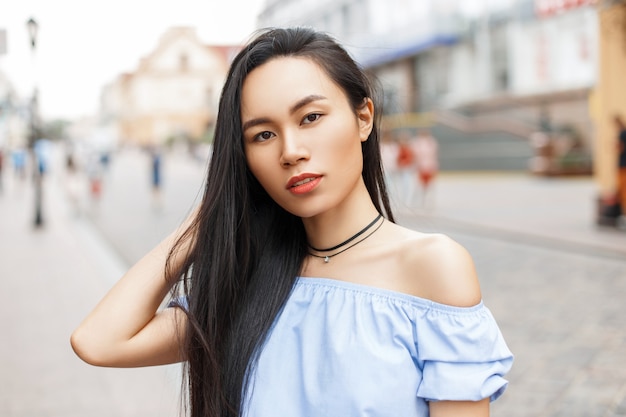 Linda mulher asiática com cabelo comprido, posando em uma cidade.