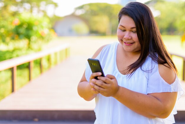 Linda mulher asiática com excesso de peso relaxando no parque