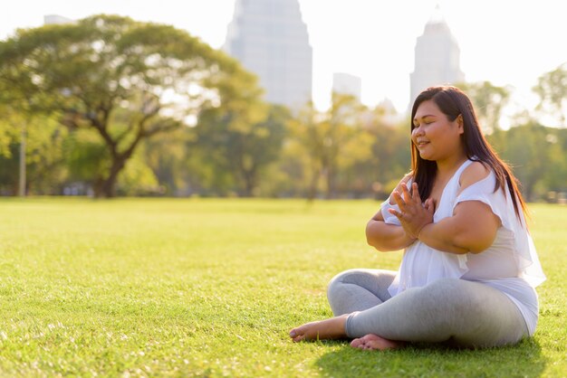 Linda mulher asiática com excesso de peso relaxando no parque