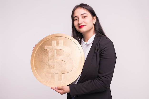 Linda mulher asiática com lábios vermelhos, segurando um grande bitcoin em branco.