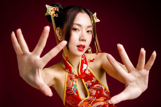 Linda mulher asiática com pele limpa e fresca vestindo cheongsam qipao posando em fundo vermelho Retrato de modelo feminino em estúdio Feliz ano novo chinês