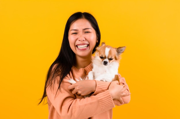 Linda mulher asiática com seu chihuahua amante de cães chihuahua A felicidade de uma garota que ama seu cachorro O amor de pessoas e cães fofos sessão de fotos no estúdio laranja