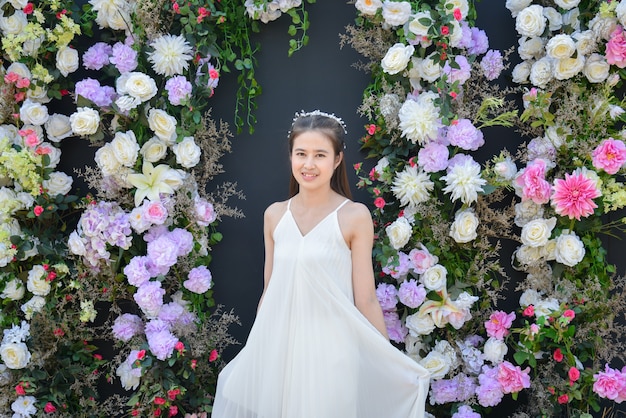 Linda mulher asiática com vestido branco em frente a um fundo de cor preta com flor.