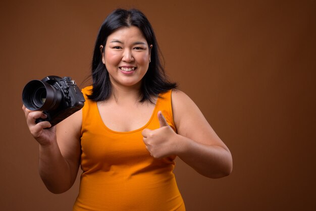 linda mulher asiática com vestido laranja sem mangas em marrom