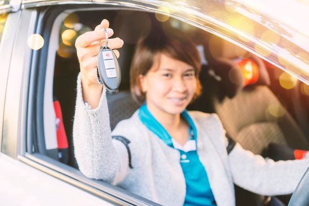 Linda mulher asiática Ela está dirigindo seu carro novo Felizmente mostrando a chave remota do carro
