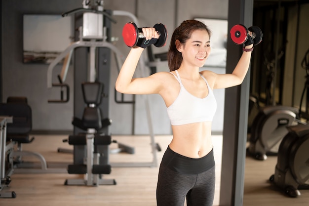 Linda mulher asiática está fazendo exercício no ginásio