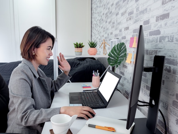 Linda mulher asiática feliz trabalhando com o computador portátil no quarto dela, condomínio.