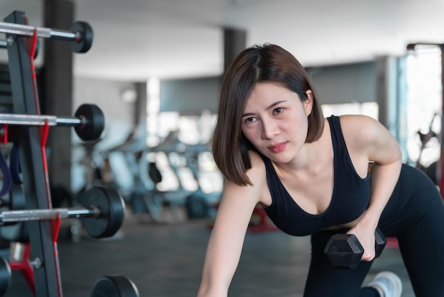Linda mulher asiática joga fitness na academiaA menina da Tailândia tem um corpo esbeltoTempo para o exercícioAs pessoas adoram a saúdeEsticar o corpo antes do treinoMulher esportiva aquecer o corpoempurrar com haltere