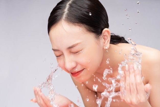 Linda mulher asiática lavando o rosto com água pura