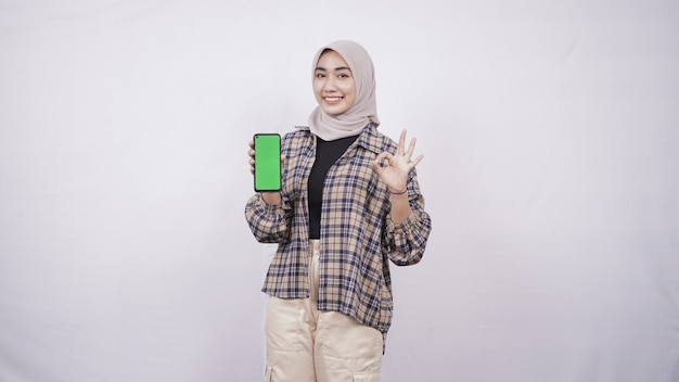 Linda mulher asiática mostrando a tela do smartphone gesticulando bem, isolado no fundo branco