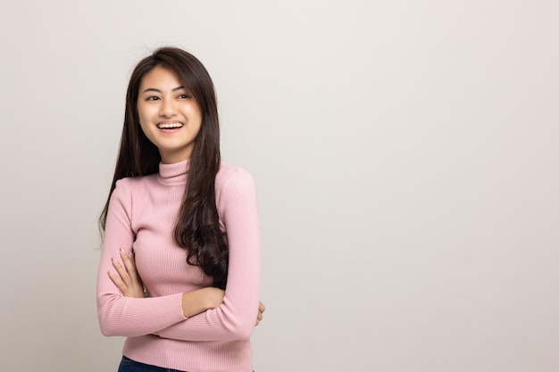 Linda mulher asiática olha para o espaço em branco Mulher sorridente vestindo camisa rosa em fundo branco isolado Garota adolescente atraente olhando para o espaço vazio para texto se sentindo animado e surpreso