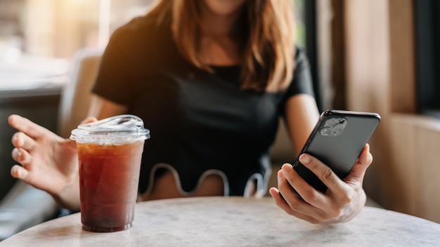 Linda mulher asiática segurando e usando tablet digital enquanto bebe café no escritório em casa e cafexA