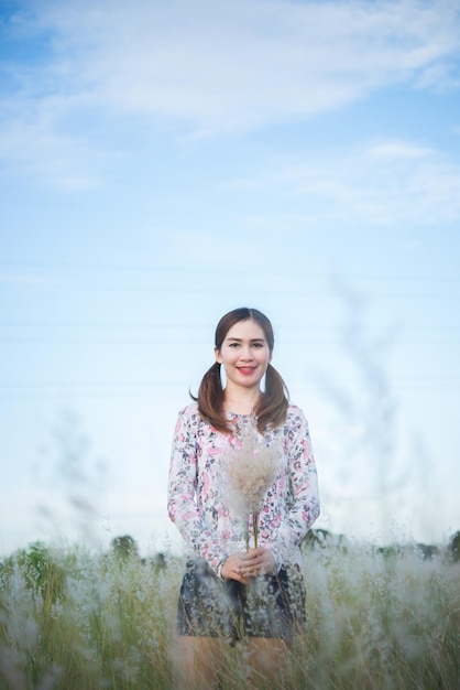 Linda mulher asiática segurando flor de grama no campo à noiteTailândia