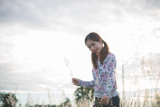 Linda mulher asiática segurando flor de grama no campo à noiteTailândia