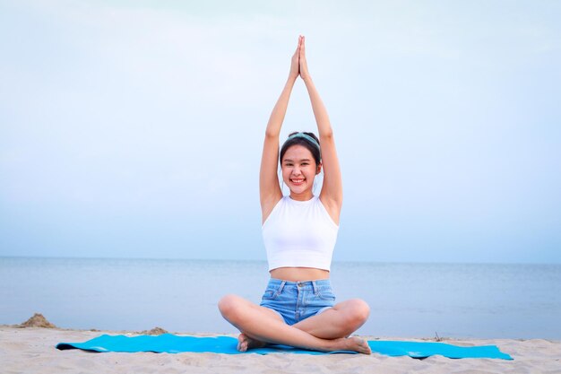 Foto linda mulher asiática sentada na praia exercitando e praticando ioga