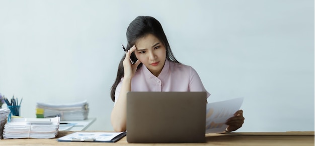 Linda mulher asiática trabalhando com computadores no escritório de uma empresa iniciante ela é funcionária de finanças da empresa trabalhando no departamento financeiro Conceito de mulheres que trabalham em uma empresa