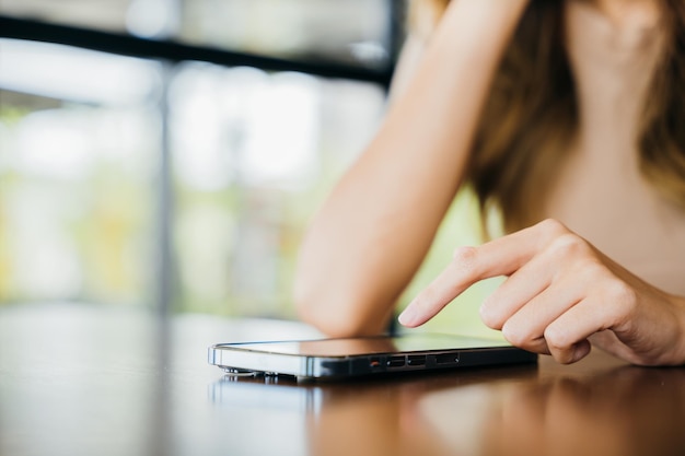 Linda mulher asiática transferiu dinheiro financeiro internet banking no celular, jovem usando telefone inteligente para fazer compras on-line no café café perto de janelas pela manhã