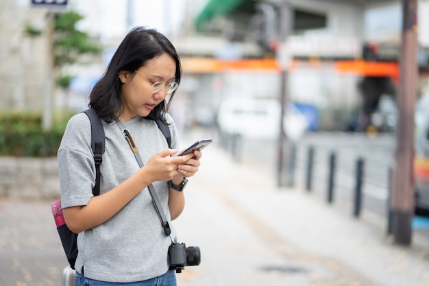 Linda mulher asiática Traveler usa um smartphone no centro da cidade para pesquisar