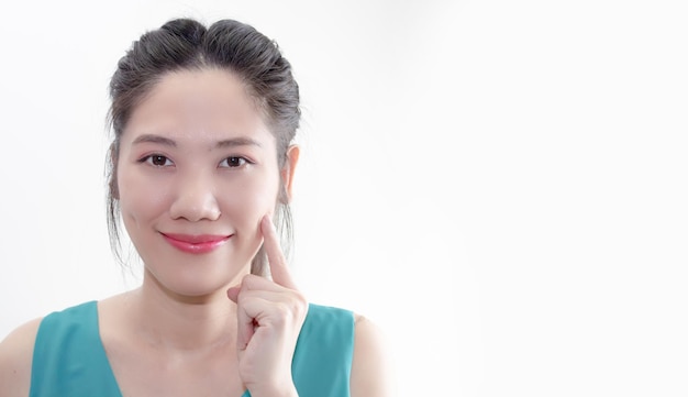 Linda mulher asiática usa o toque do dedo na bochecha com sorriso e feliz com uma boa saúde de sua pele
