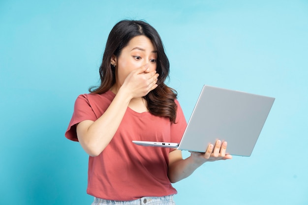 Linda mulher asiática usando laptop com uma cara de surpresa