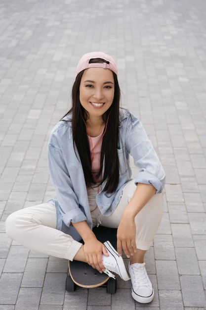 Linda mulher asiática usando roupas casuais sentada no skate