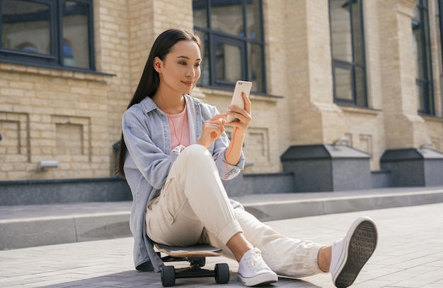 Linda mulher asiática usando telefone celular, ouvindo música ao ar livre