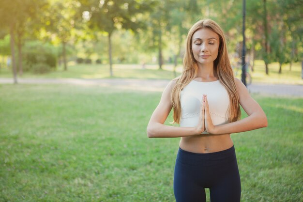 Linda mulher atlética fazendo yoga no parque