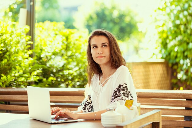 Linda mulher atraente no café com um laptop tendo uma pausa para café