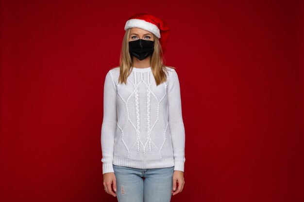 Linda mulher branca com suéter branco e chapéu de natal com medo de contrair o vírus