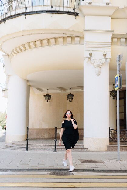 Linda mulher branca em um vestido preto em um fundo de uma paisagem urbana