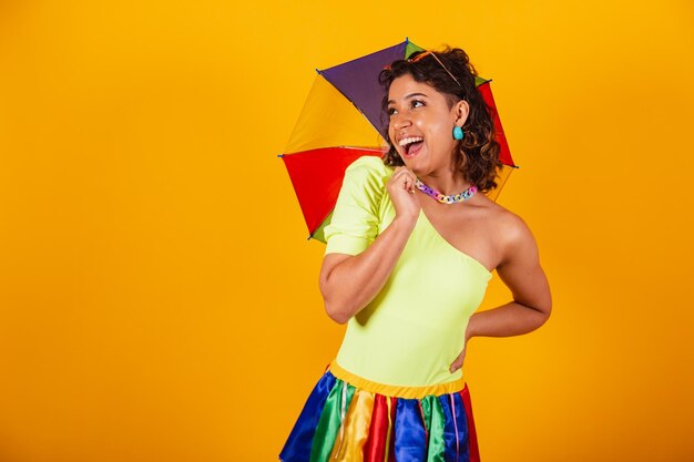 Linda mulher brasileira afro-americana em roupas de carnaval torcendo usando guarda-sol colorido