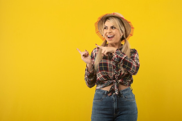 Linda mulher brasileira com roupas de festa junina em fundo amarelo