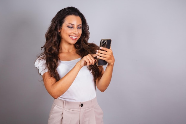 Linda mulher brasileira segurando smartphone usando aplicativos de telefone celular