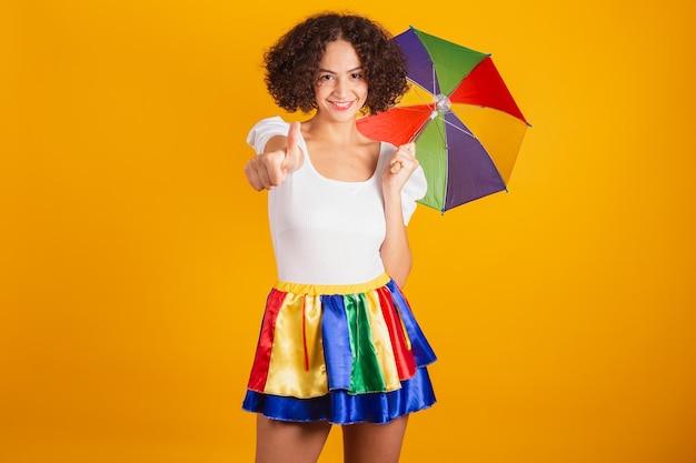 Linda mulher brasileira vestida com roupas de carnaval saia colorida e camisa branca como sinal positivo