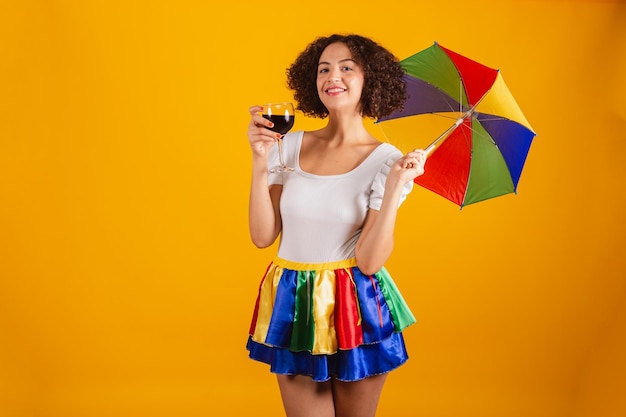 Linda mulher brasileira vestida com roupas de carnaval saia colorida e camisa branca frevo guarda-chuva segurando copo de vinho