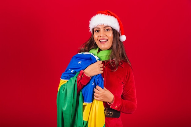 Linda mulher brasileira vestida com roupas de Natal Papai Noel segurando a bandeira do Brasil