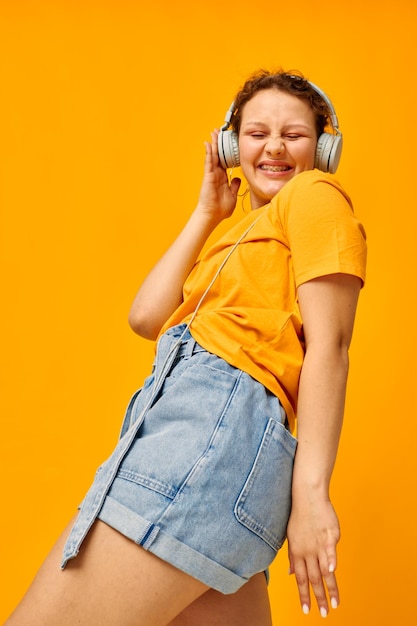Linda mulher camiseta amarela fones de ouvido entretenimento música diversão fundos isolados inalterados