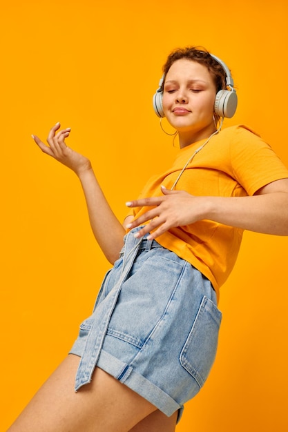 Linda mulher camiseta amarela fones de ouvido entretenimento música diversão fundos isolados inalterados