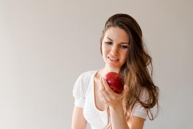 Linda mulher caucasiana casual está prestes a morder uma maçã na cozinha um jovem